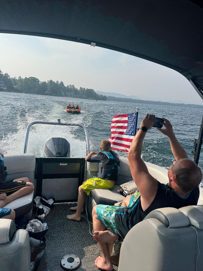 people on boat watching group being pulled in a tube