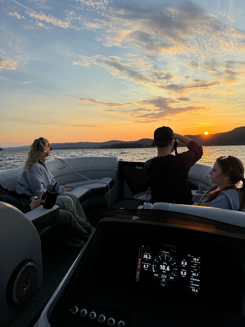people on a lake boat looking at a sunset