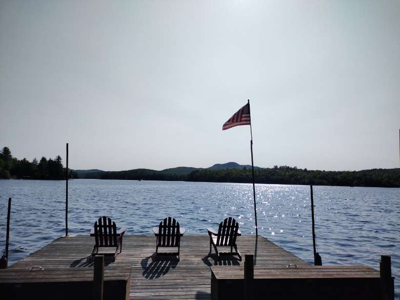 a dock with three chairs and a flag on it