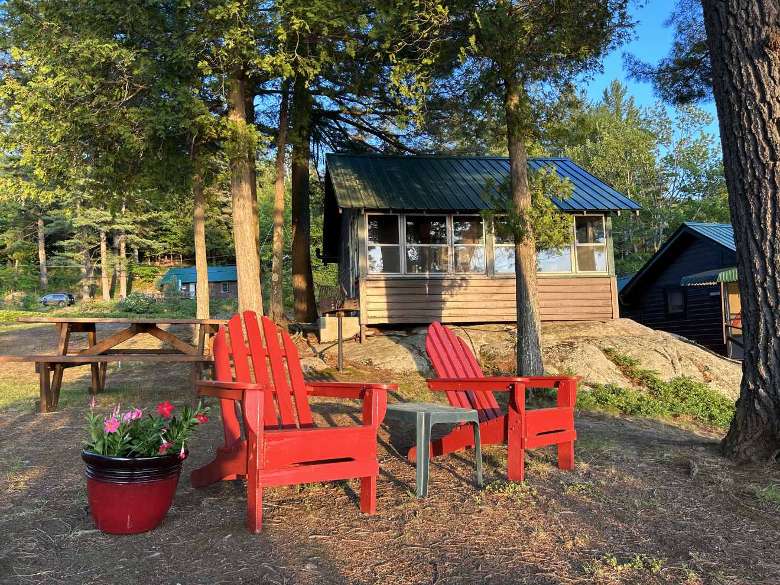 two red adirondack chairs in front of a cabin
