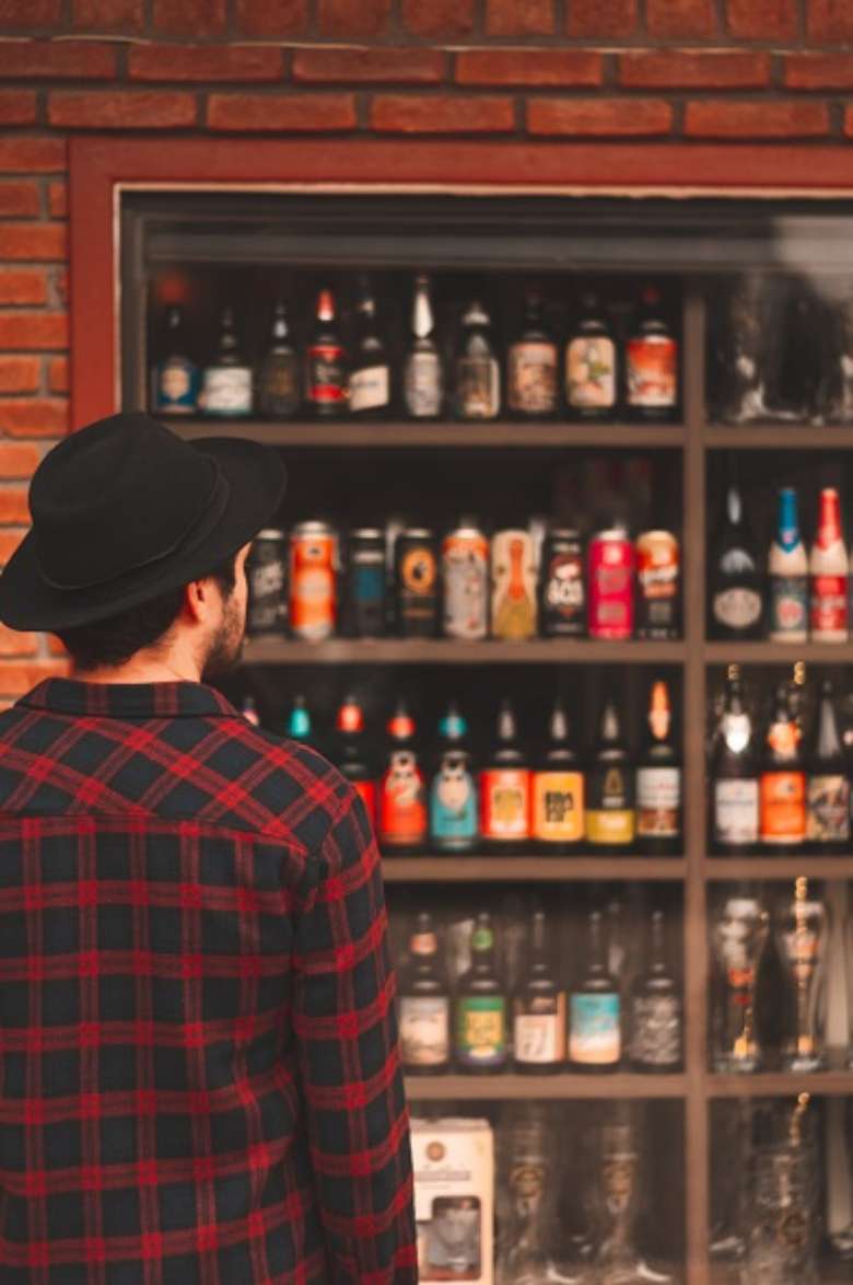man looking at a variety of beer cans and bottles