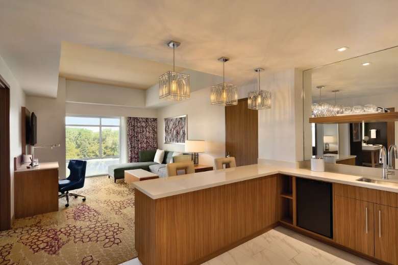 a large hotel suite with a wet bar, living room, workspace, and more features