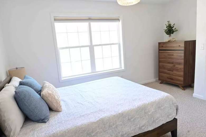 bedroom in a house with a bed, wooden dresser, and a window