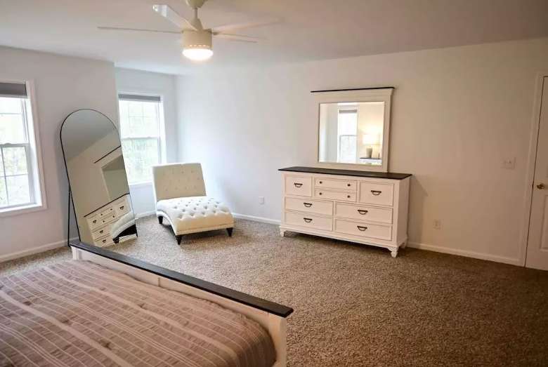 bedroom with a dresser and mirror, a bed, and a lounge chair by a mirror