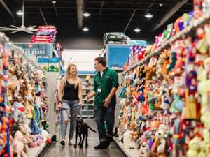 pet store employee, woman, and dog walking down an aisle