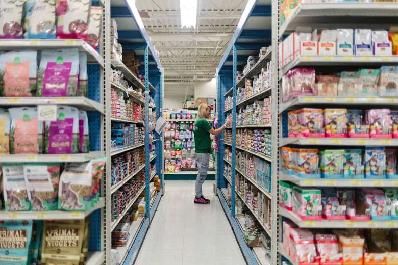 aisle in a pet store with a person looking at food