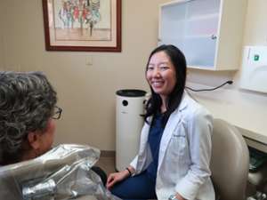 female dentist smiling while seated next to a patient
