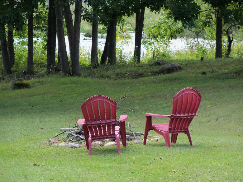 two red adirondack chairs around a fire pit