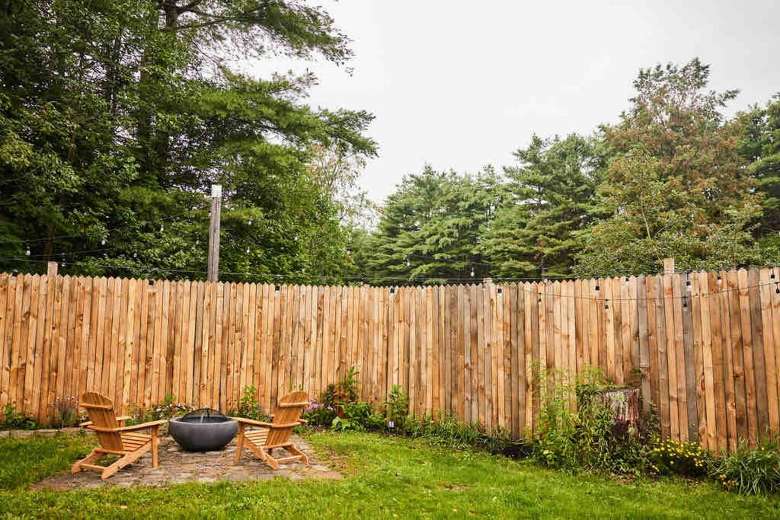 backyard with a fence, fire pit, and two adirondack chairs