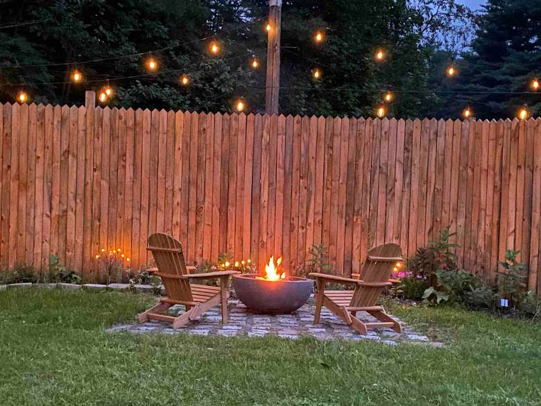 Backyard with a fence, fire pit, and two adirondack chairs