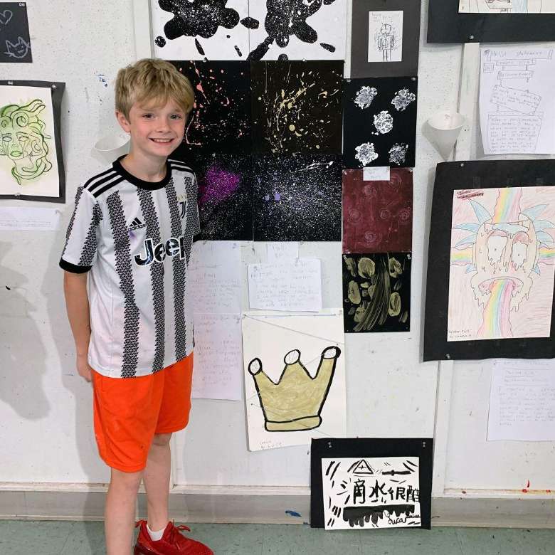child standing next to art