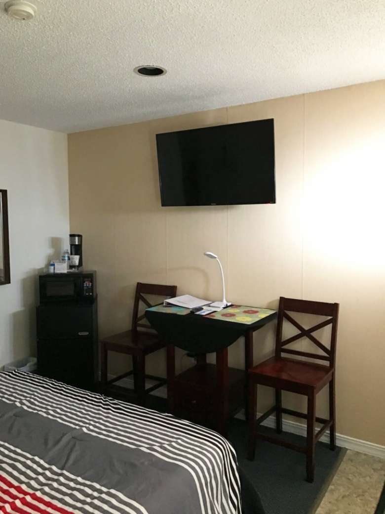 interior of a motel room with a desk and TV