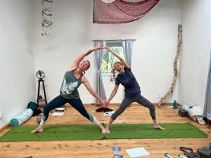 two women holding hands in a yoga studio