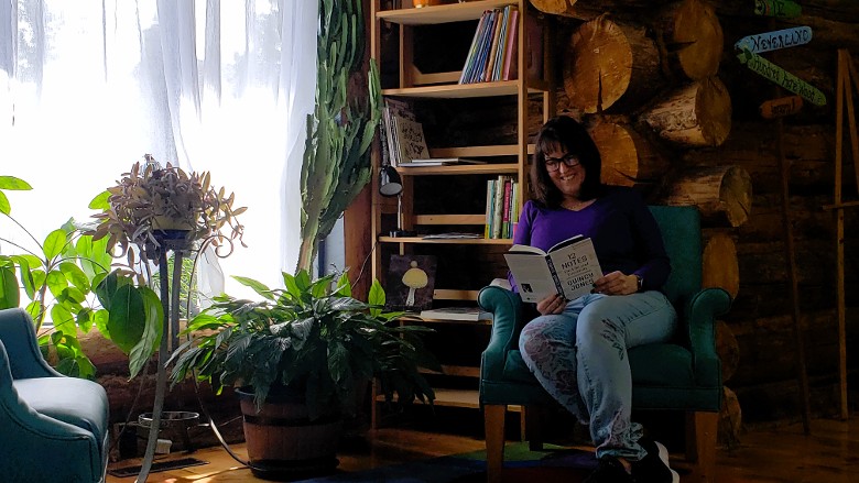 Woman reading while sitting in a chair by a sunny window