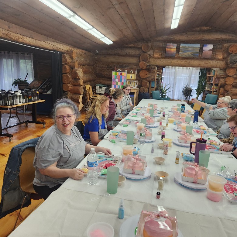 people seated at a table in a log cabin decorating cakes