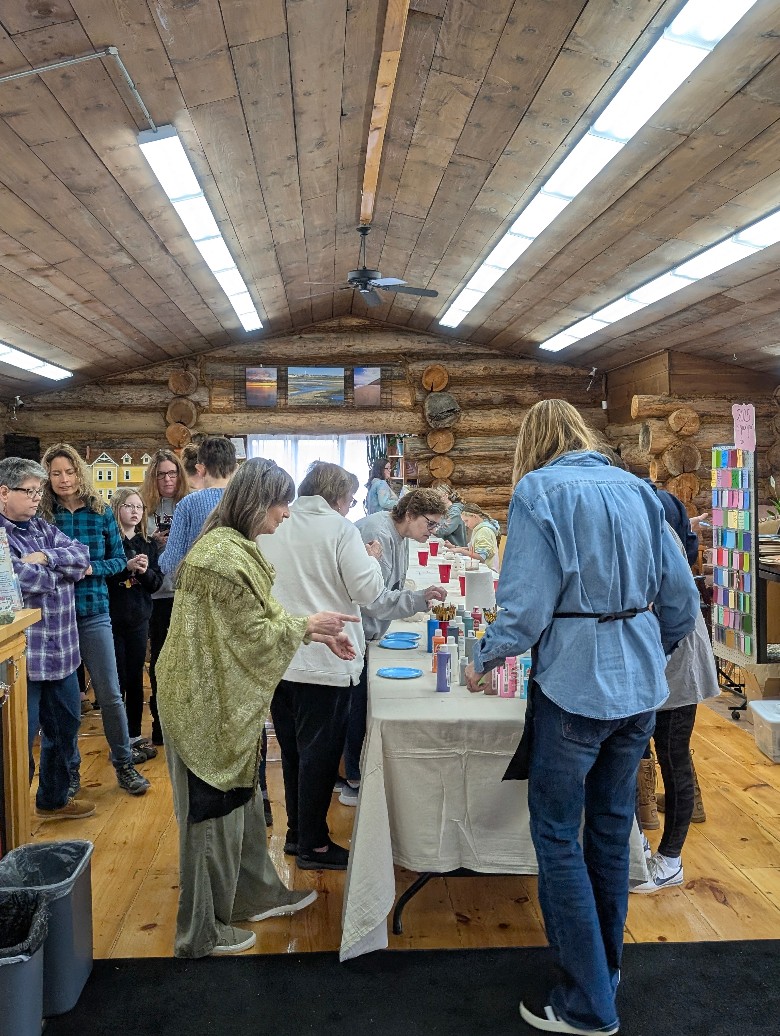 Log cabin with people around a table of paints