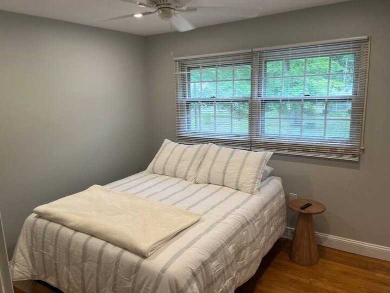 bedroom with a bed with two windows behind it