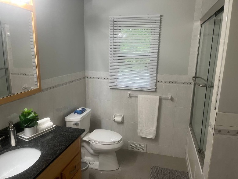 bathroom with toilet, window, sink, and shower