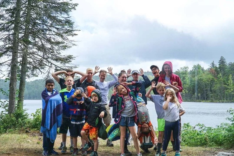 group of adults and kids making funny faces by the lake