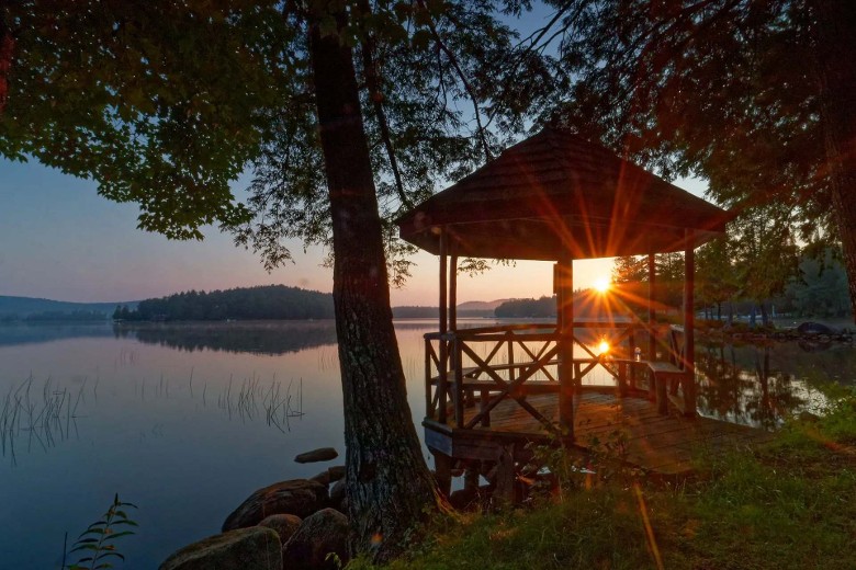 sunrise light shining through a gazebo by the lake