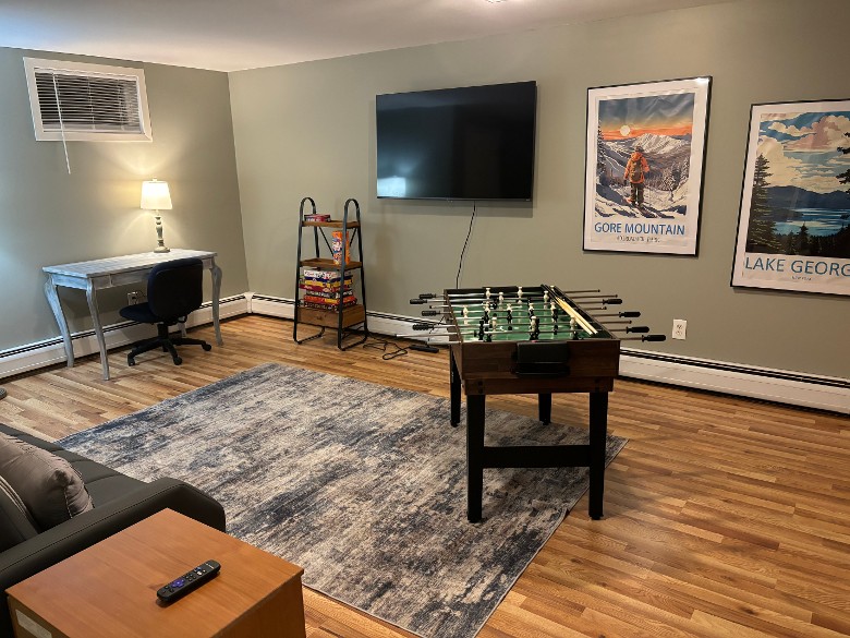 lounge area with pictures on the wall, a desk and chair, a TV, and a foosball table