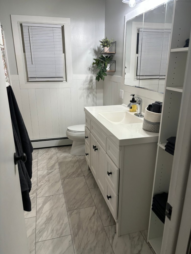 bathroom with a white sink, white toilet, and closed window blind