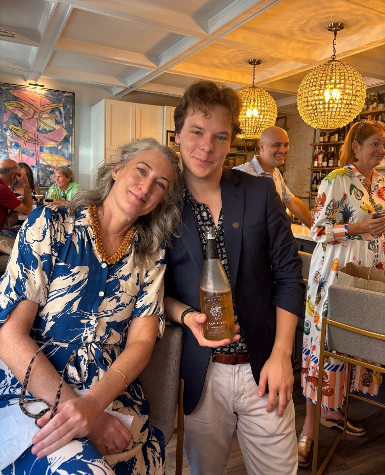 two people posing with a bottle of champagne