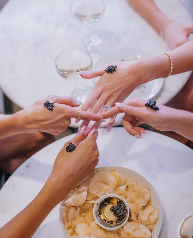 women crossing fingers above plates