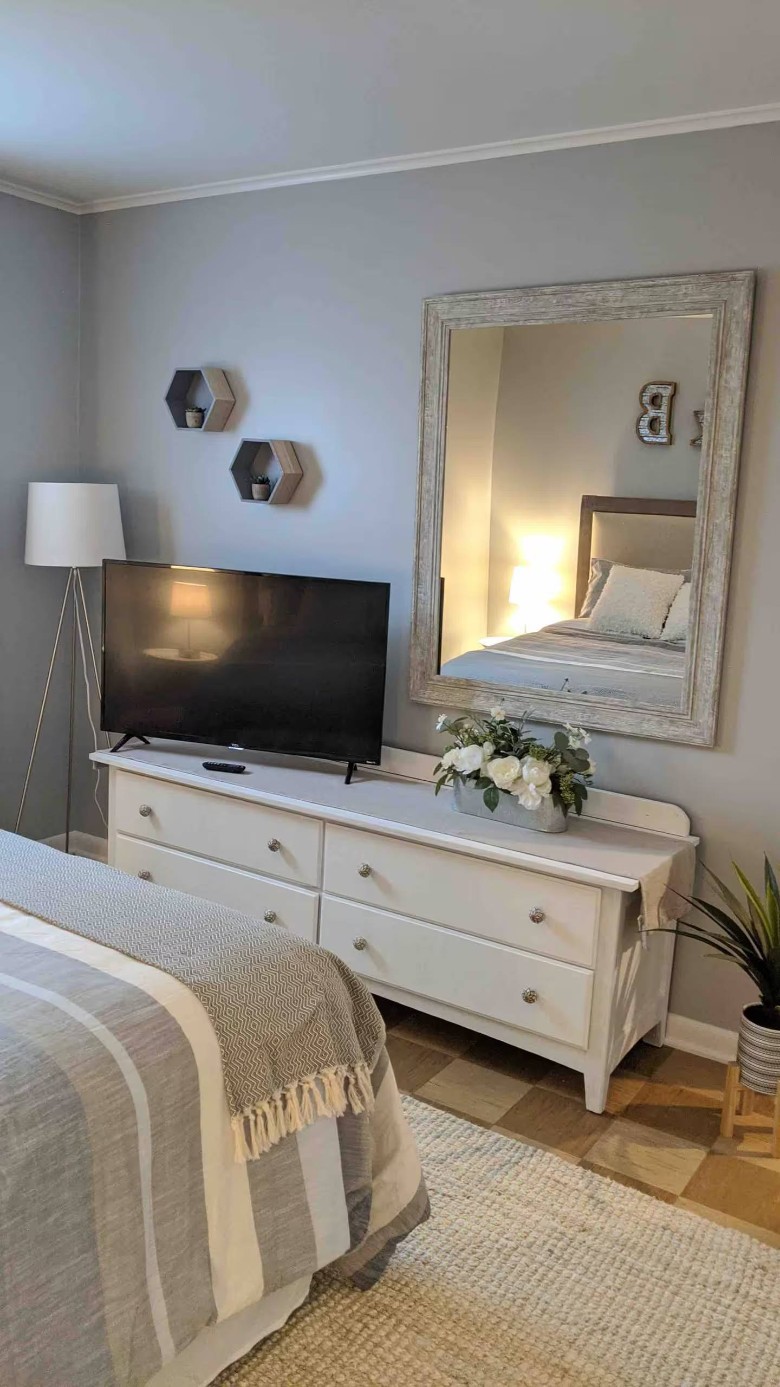 bedroom with a white dresser with a TV on top and a mirror on the wall