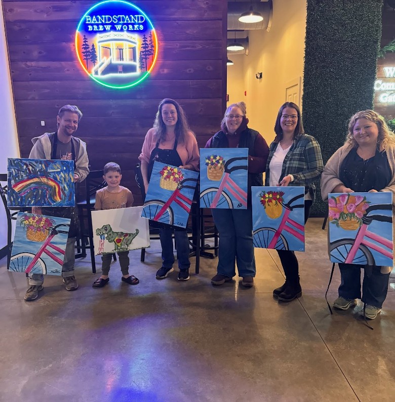 people holding up paintings after a paint and sip session