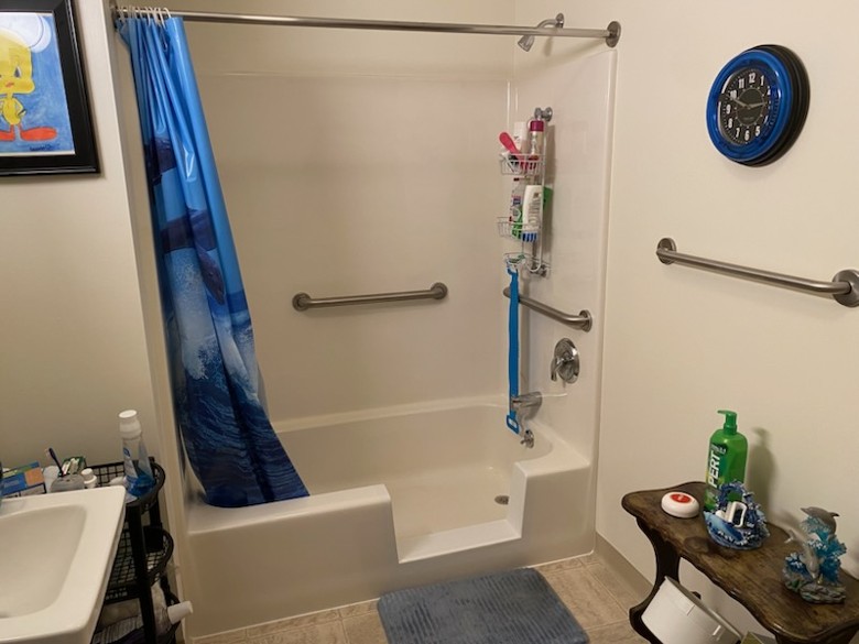 tub to shower conversion with blue shower curtain, sink nearby, and clock on wall
