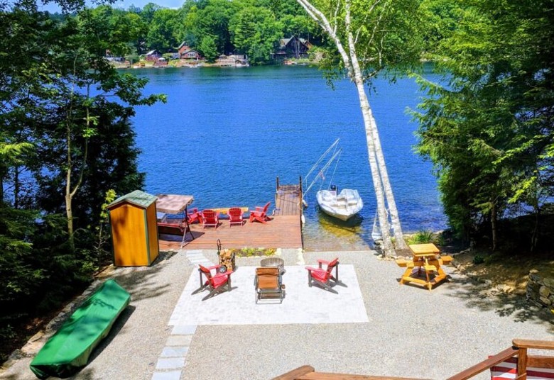 view of backyard with lake access, adirondack chairs, boat