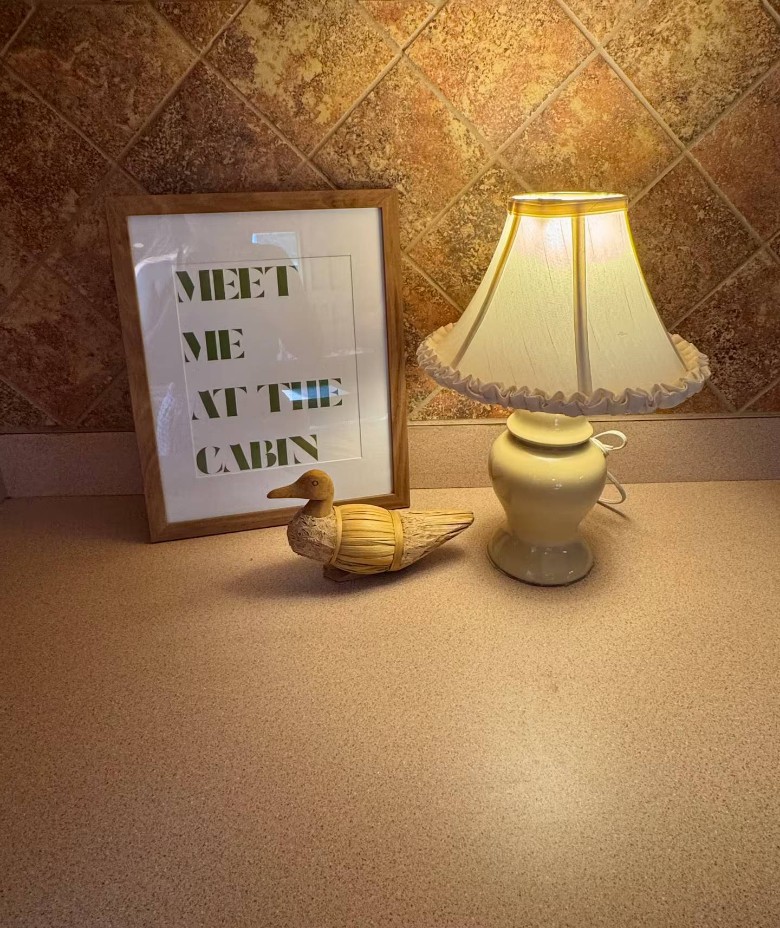 meet me at the cabin sign by lamp and decorative duck