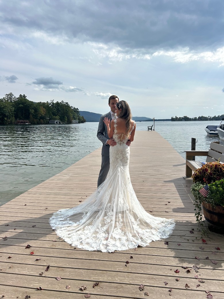 bride and groom standing on a lake dock