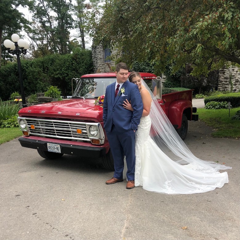 bride and groom standing by a red truck