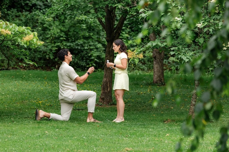 man proposing to woman in wooded field