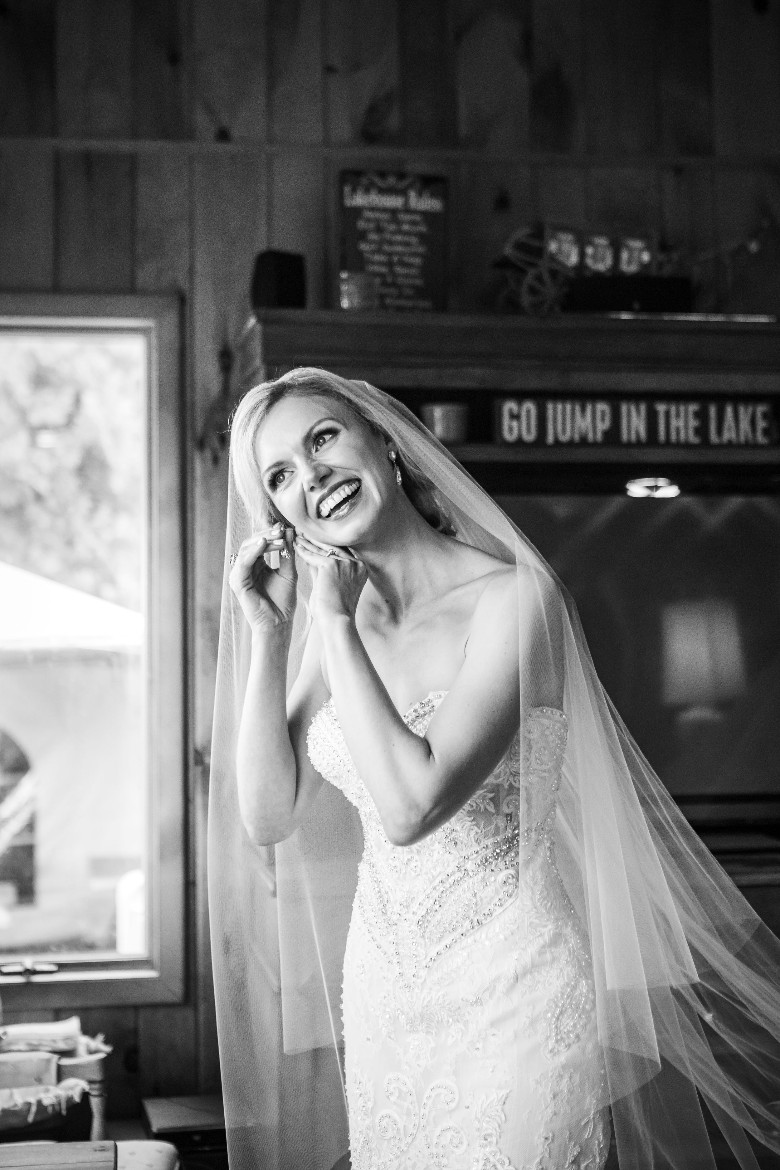 black and white photo of a bride in bridal room getting earrings on