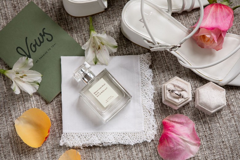 bride's shoes, ring and box, flower petals, and perfume bottle