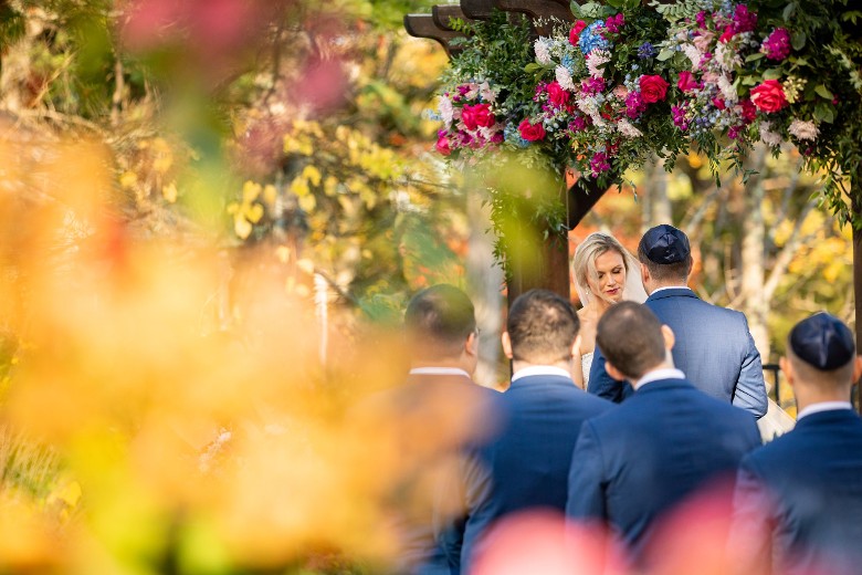 focused view of bride and groom from behind flowers