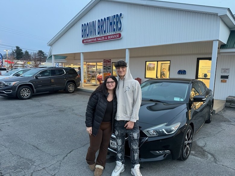 couple poses by car they just bought