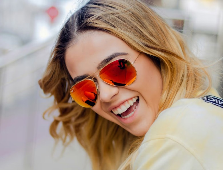 a woman smiling and wearing sunglasses