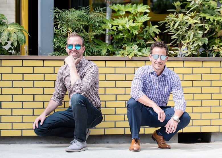 two guys wearing sunglasses in front of yellow wall