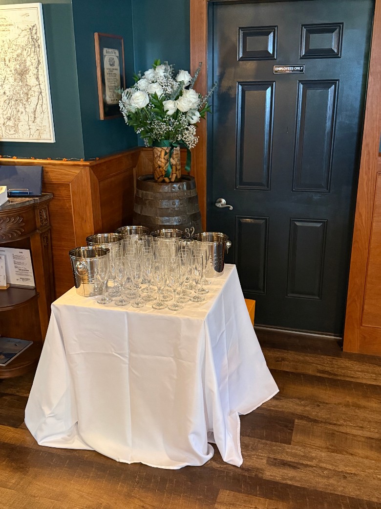 a table with drink glasses near a black door and flowers