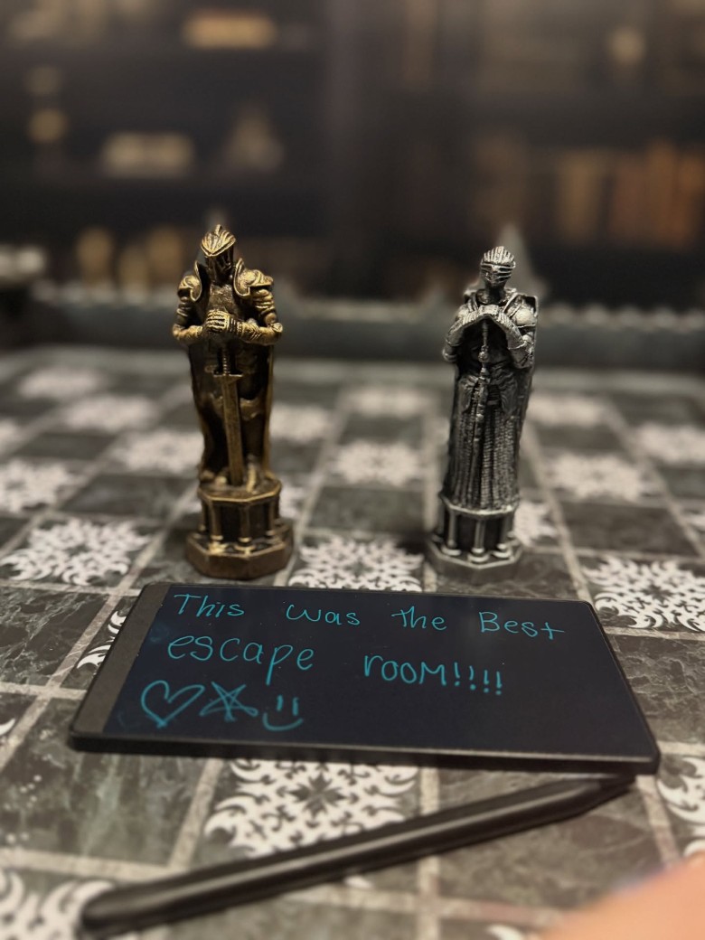 two figurines on a board with escape room message