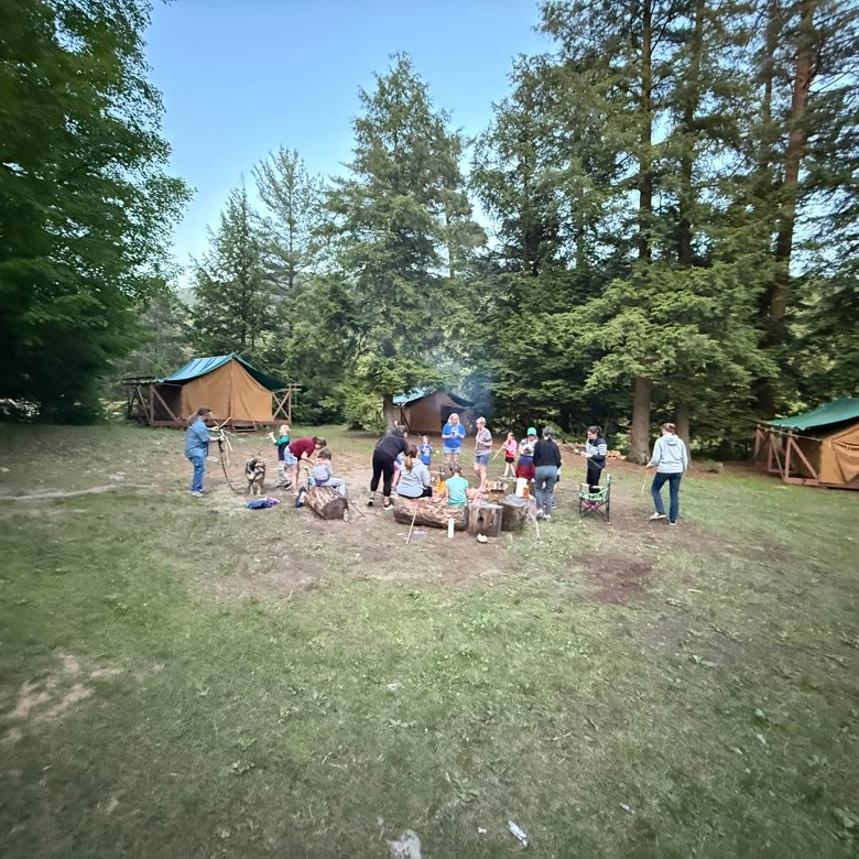 a group of people around a campfire near tents