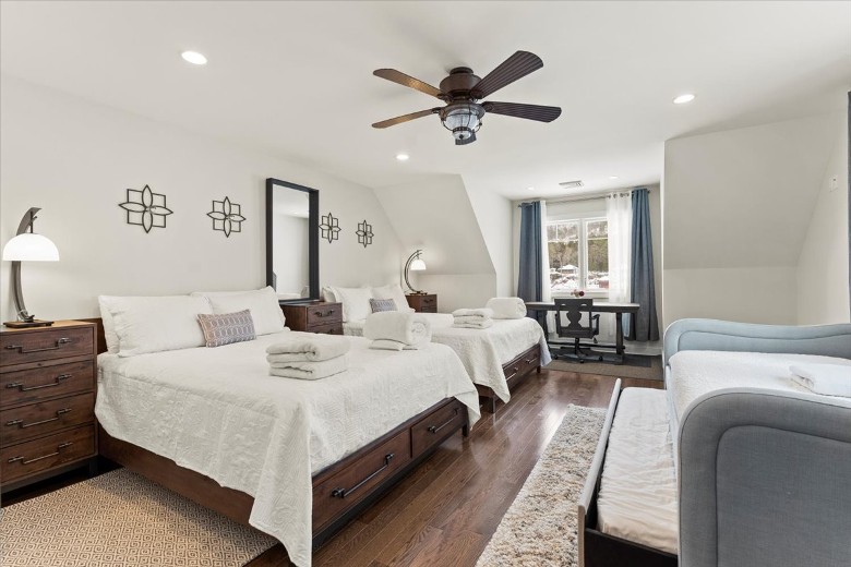 Second level bedroom featuring two full beds and a twin bed with a trundle with lake views.