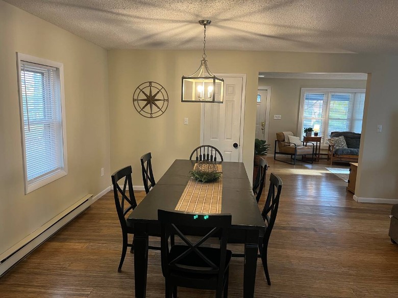 a dining room in a house with a black wooden table, black chairs around it, and an overhanging light fixture