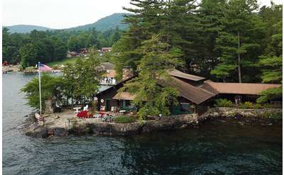 an aerial view of Beckley's Lakeside Log Cabins situated right on the lake, surrounded by trees