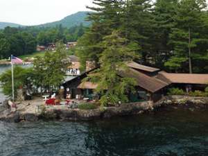 an aerial view of Beckley's Lakeside Log Cabins situated right on the lake, surrounded by trees