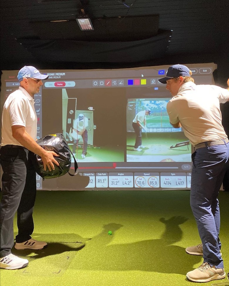 indoor golf instructor and man preparing to swing